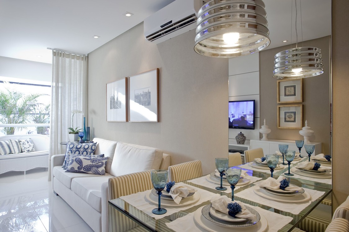 Sala de jantar com mesa posta em tons de azul e sala de estar ao fundo