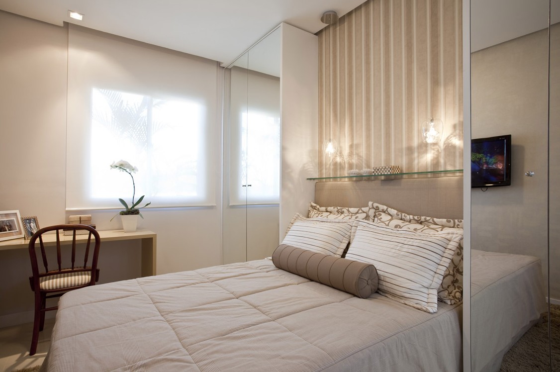 Quarto de casal em tons neutros com cabeceira estofada e mesa de apoio